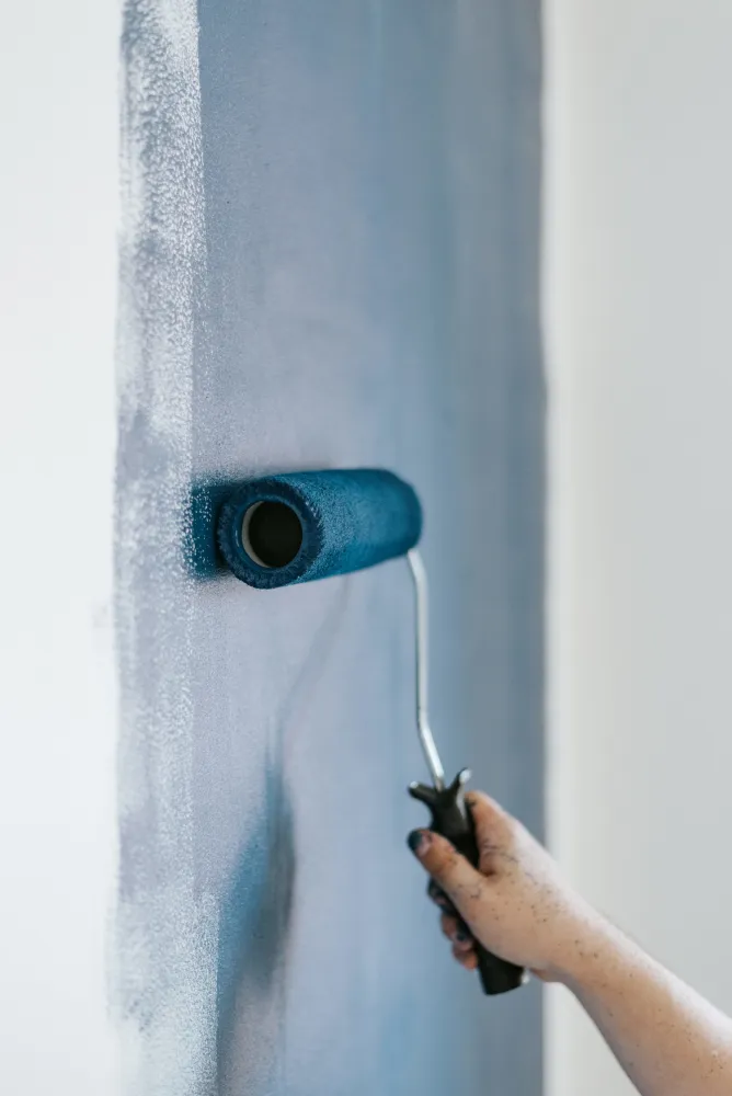 Pintor a pintar uma parede interior com rolo