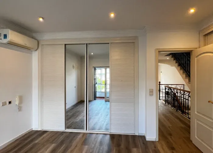 Quarto pintado de branco com roupeiro espelhado, pronto a usar